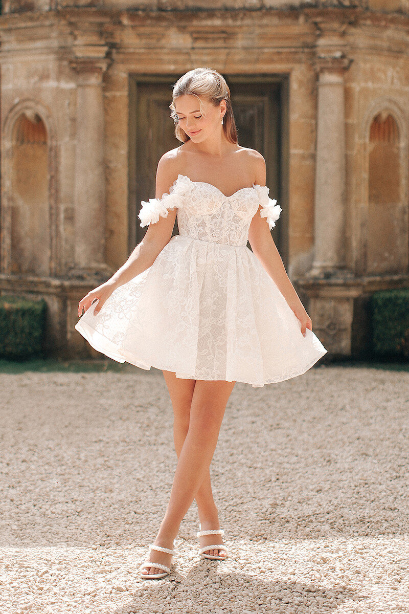 Woman in bridal dresses poses and looks off into the distance.