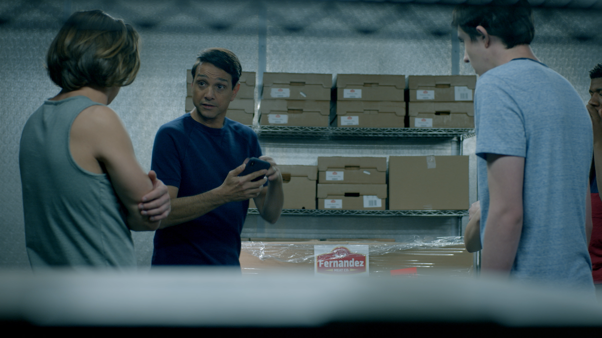 A picture of Daniel and two students in a warehouse with Fernandez meat boxes behind them.