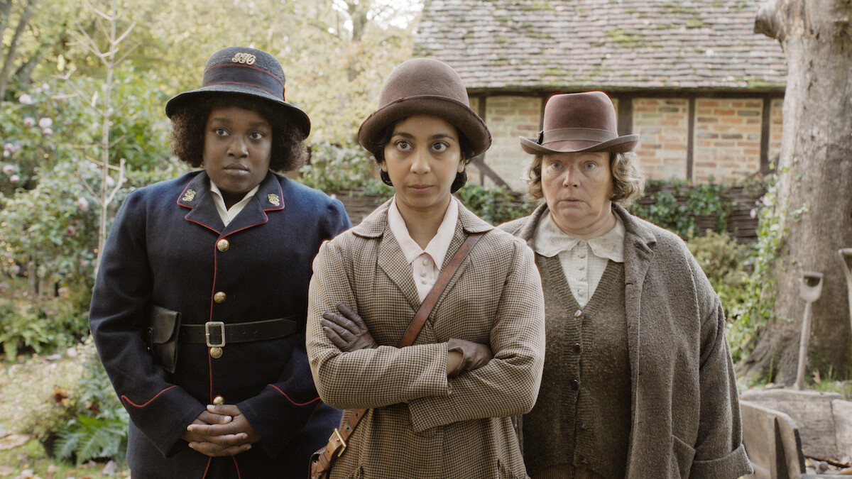 Lolly Adefope as Kate, Anjana Vasan as Gladys Moss, and Joanna Scanlan as Ann stand together outdoors with concerned expressions in ‘Wicked Little Letters.’