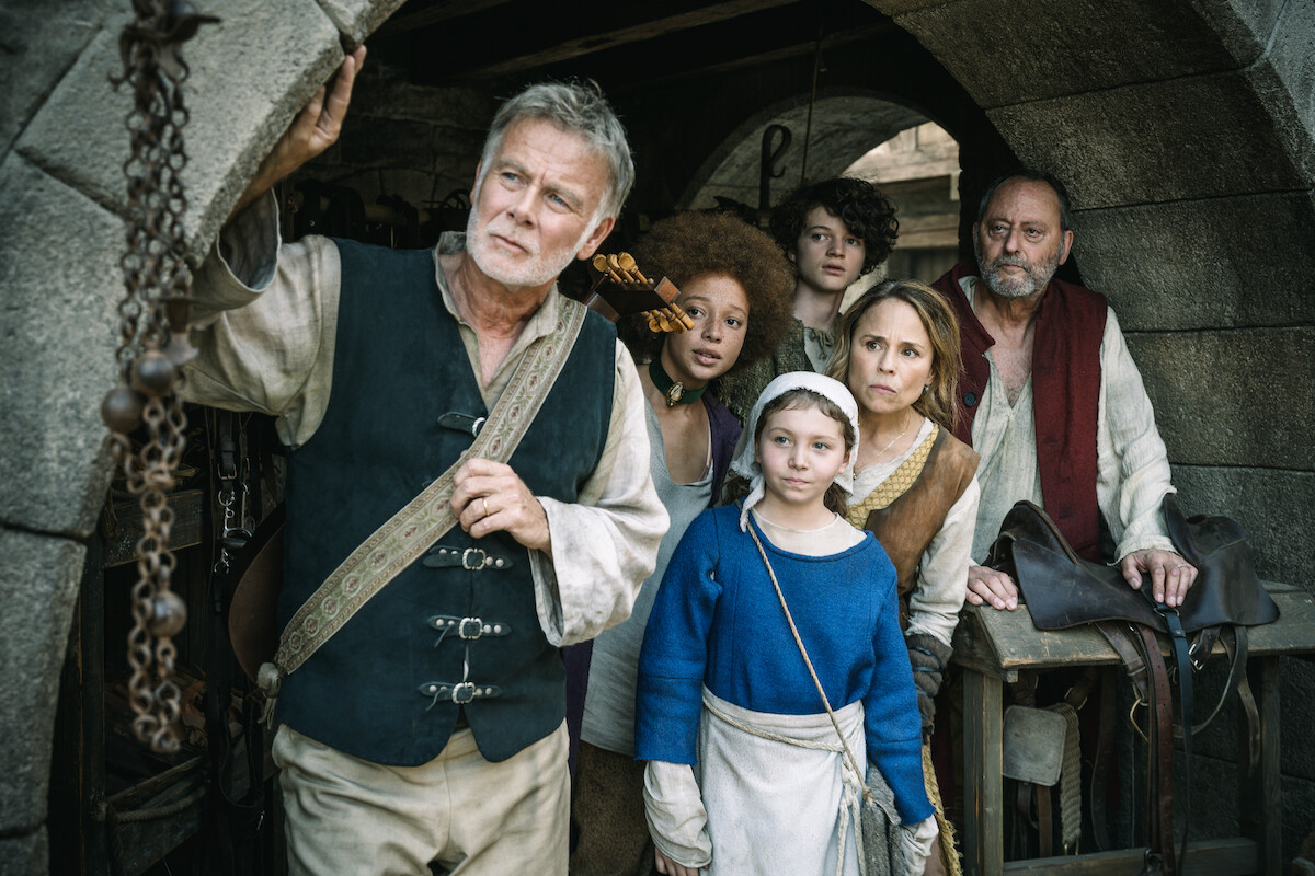 From left to right, Franck Dubosc, Lisa Do Couto, Alizée Caugnies (bottom), Raphael Romand (top), Suzanne Clément, and Jean Reno, who all wear medieval period costumes while standing under a brick archway.
