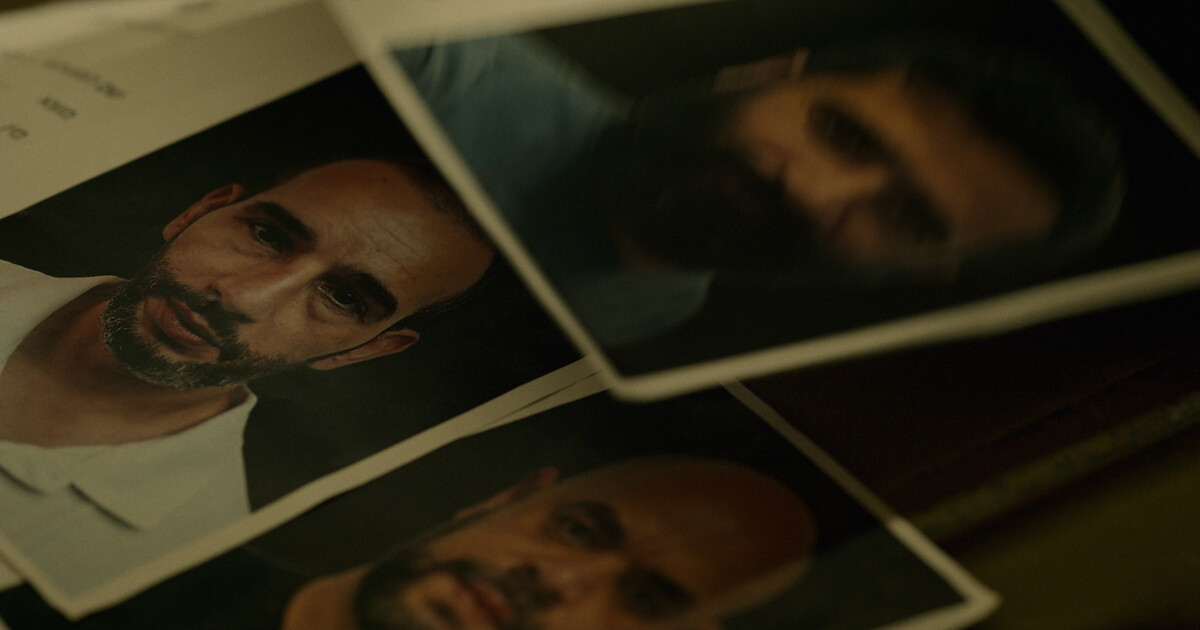 Several printed headshot photographs of men with serious expressions, arranged overlapping on a dark surface, resembling identification or investigative files in a dimly lit environment.