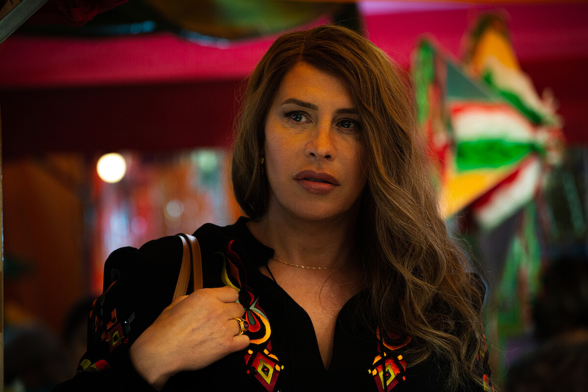 Emilia Pérez (Karla Sofía Gascón) wears a dark top and holds a brown bag to her shoulder.