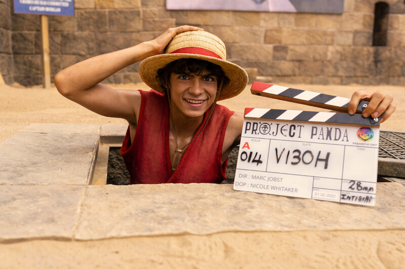Iñaki Godoy as Monkey D. Luffy smiles while holding a clapboard in Season 1 of 'One Piece.'