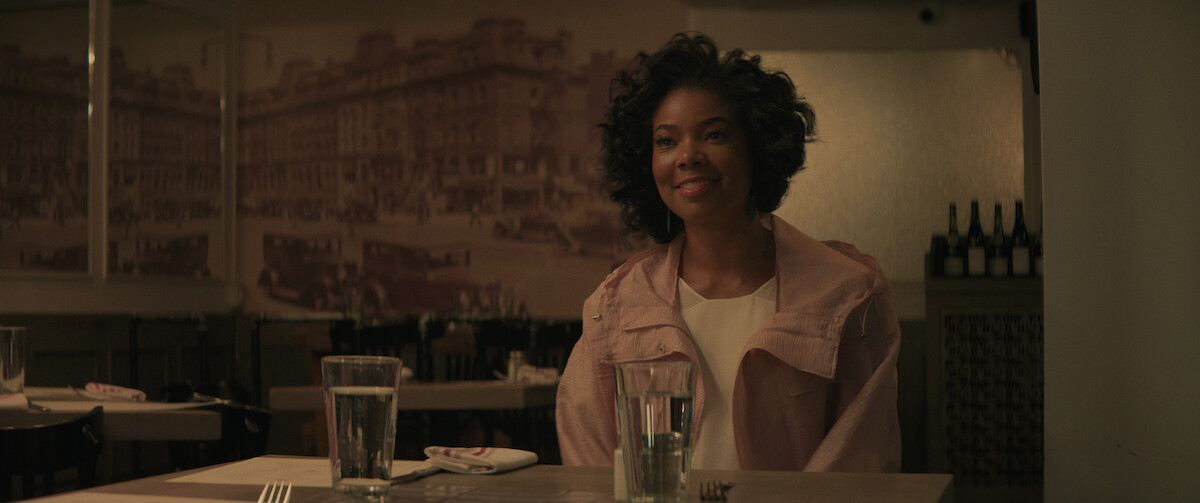 Gabrielle Union sits in a restaurant wearing a pink cropped jacket in a still from ‘The Perfect Find.’