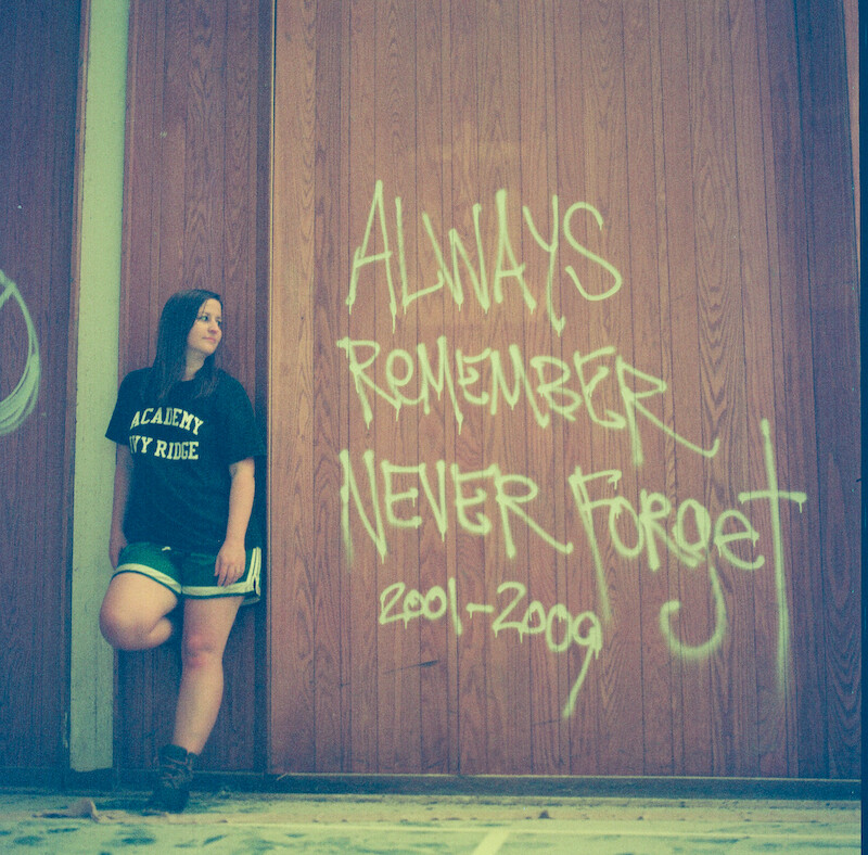 Katherine Kubler standing in front of wall graffiti at The Academy at Ivy Ridge that reads "Always remember, never forget."