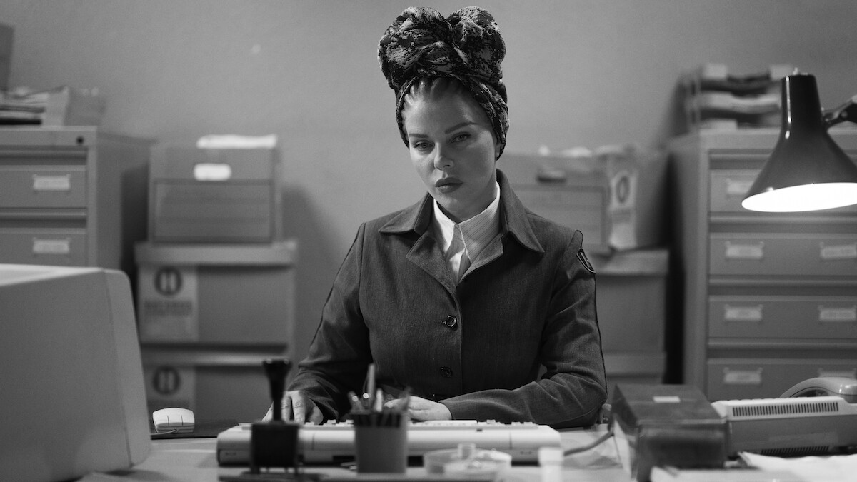 Black-and-white image of Debi Mazar as Medusa working at a desk in Season 1 of ‘Kaos’