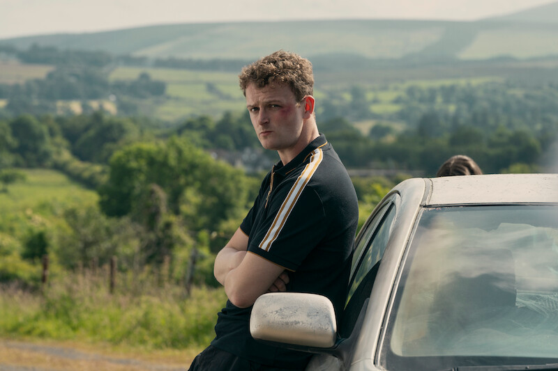 Chris Walley as Sean leans on a car in 'Bodkin'
