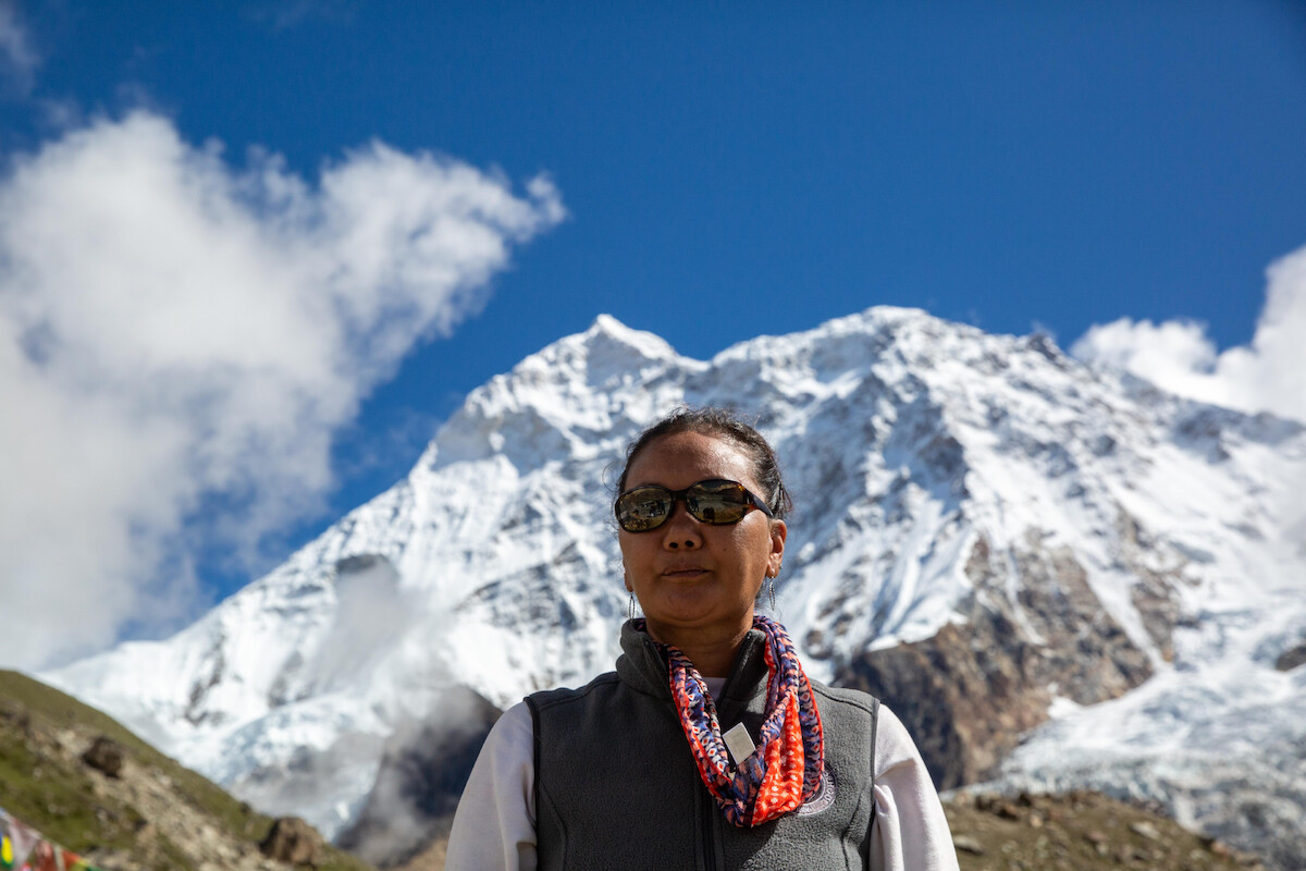 Lhakpa Sherpa in ‘Mountain Queen: The Summits of Lhakpa Sherpa’ with snow-capped mountains behind her. 