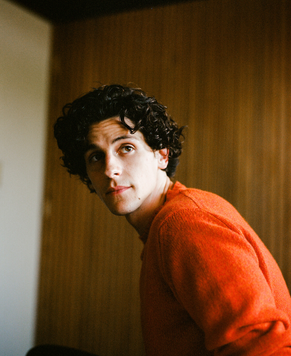 Owen Painter in an orange sweater looking off into the distance