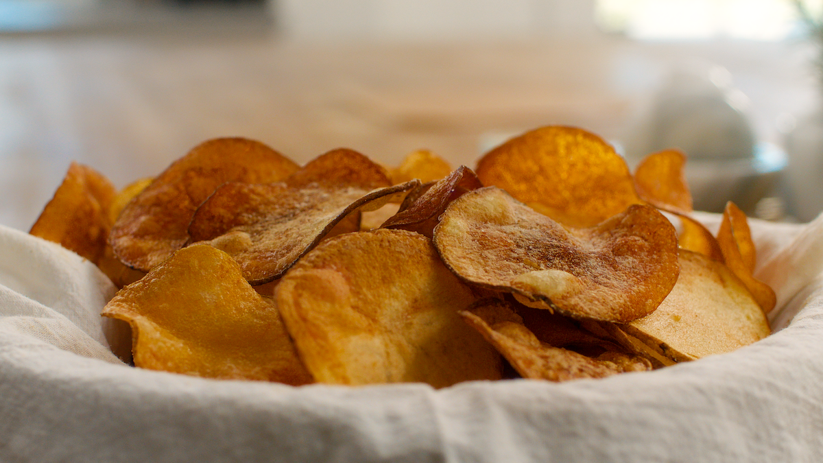 Golden fried potato chips in a cloth-lined bowl.