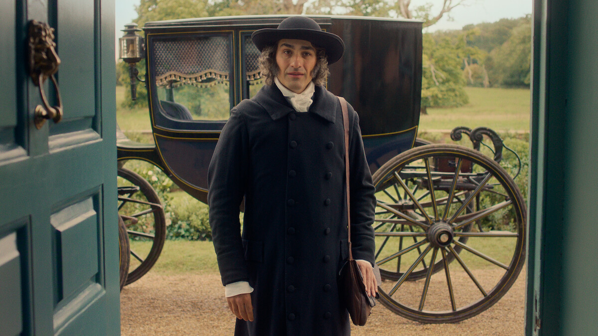 A man in historical attire stands at an open door, with a large black horse-drawn carriage and green countryside visible in the background, suggesting a period setting.