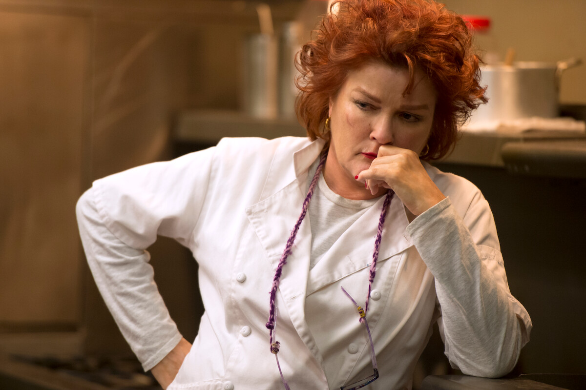 Kate Mulgrew as Red stands in a kitchen wearing a chef coat in Season 3 of ‘Orange Is the New Black.’ 