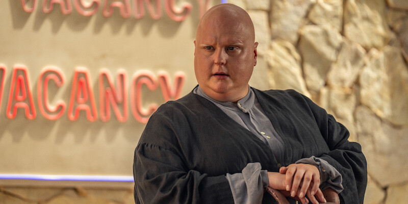 A bald man sits leaning on his arm in Seaosn 1 of 'Kaos'