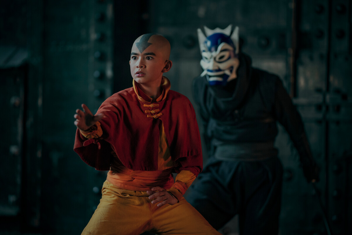 Gordon Cormier as Aang stands in a fighting pose while a figure wearing a blue mask stands behind him in season 1 of ‘Avatar: The Last Airbender’