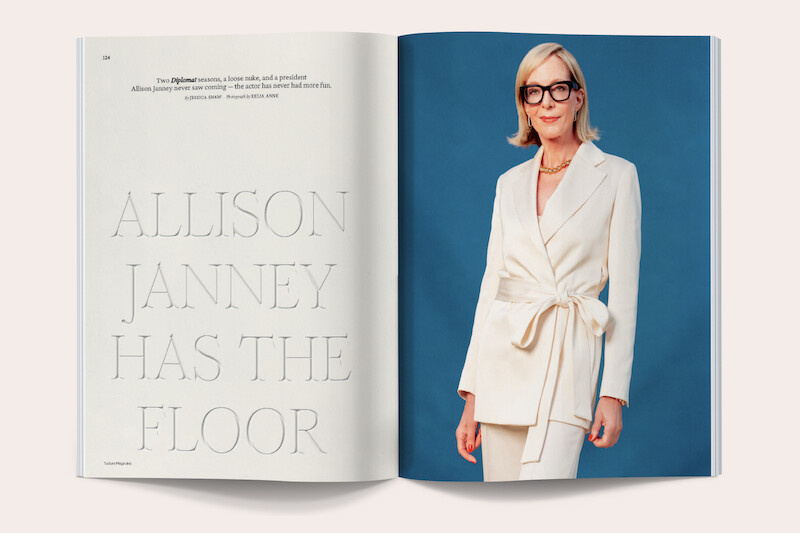 Magazine spread featuring a woman in a white suit and glasses posing against a blue background; the left page displays large text reading "ALLISON JANNEY HAS THE FLOOR" with brief editorial text above.