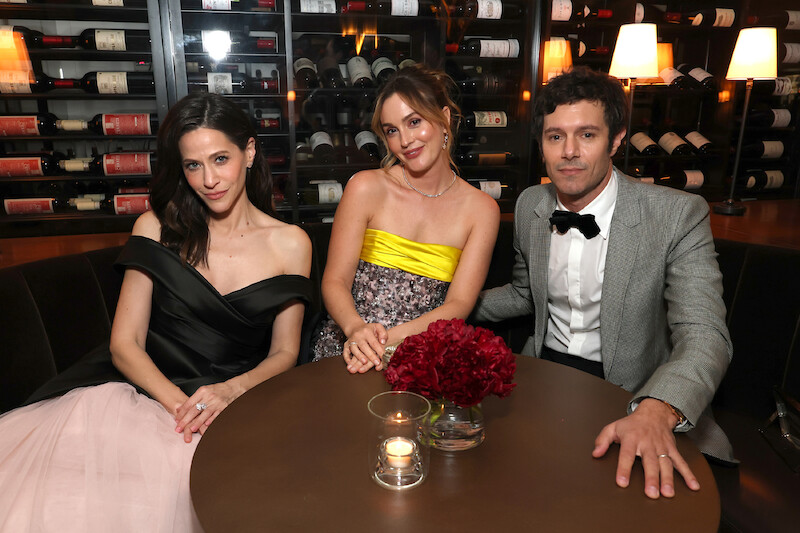 Jackie Tohn, Leighton Meester, and Adam Brody pose while seated at a table.