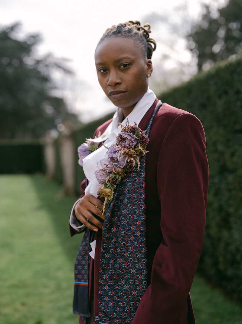 Shanti Hinton stands outside in a suit in 'The Event of the Season: A Bridgerton Wedding'