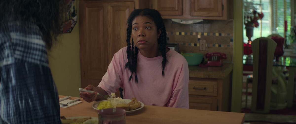 Gabrielle Union sits at a kitchen counter eating eggs in a pink sleep shirt in a still from ‘The Perfect Find.’