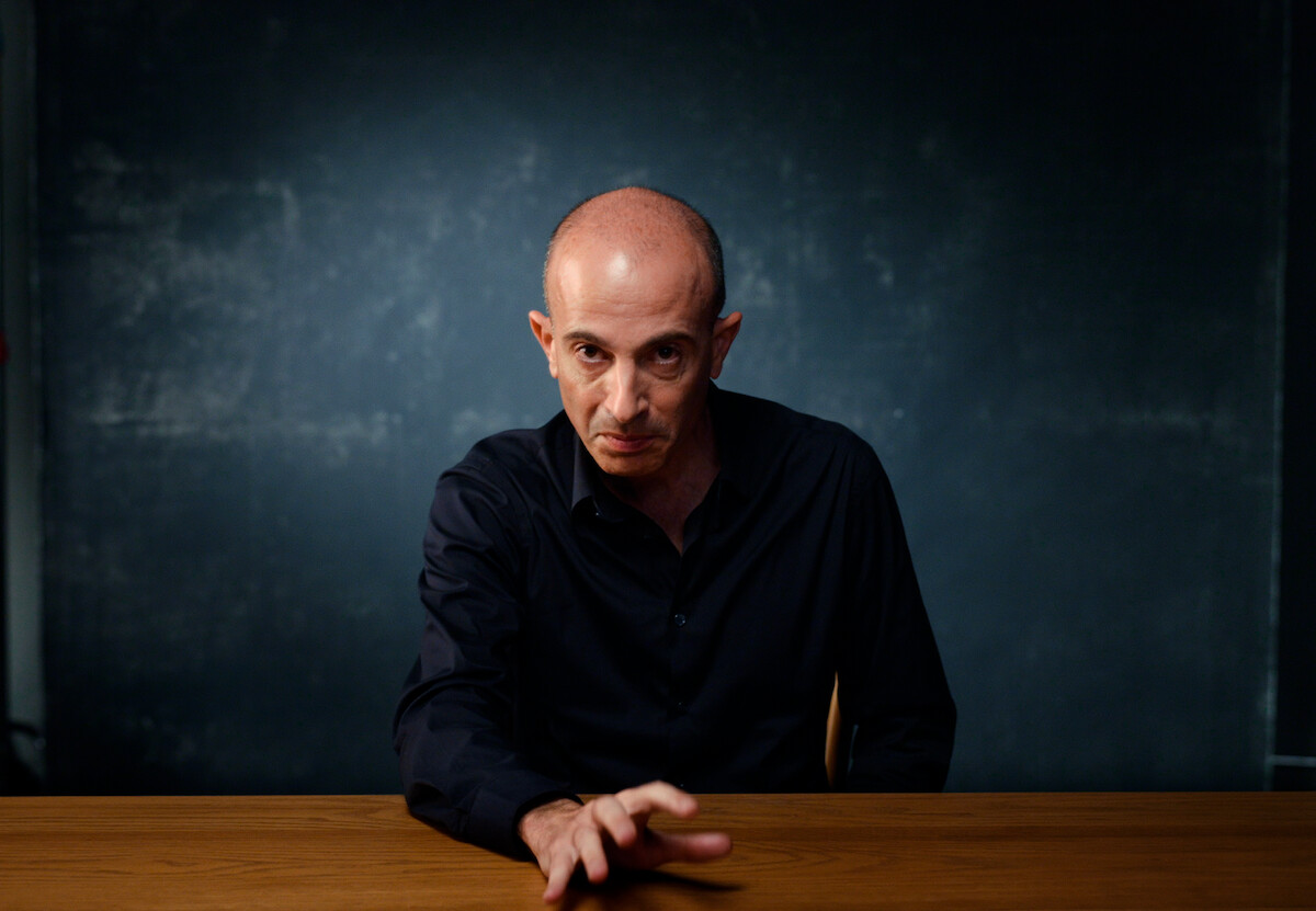 Yuval Noah é um homem branco e cxareca, ele veste camisa de manga comprida preta