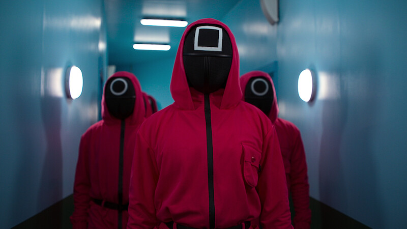 Three of the Squid Game guards wearing pink jumpsuits. 