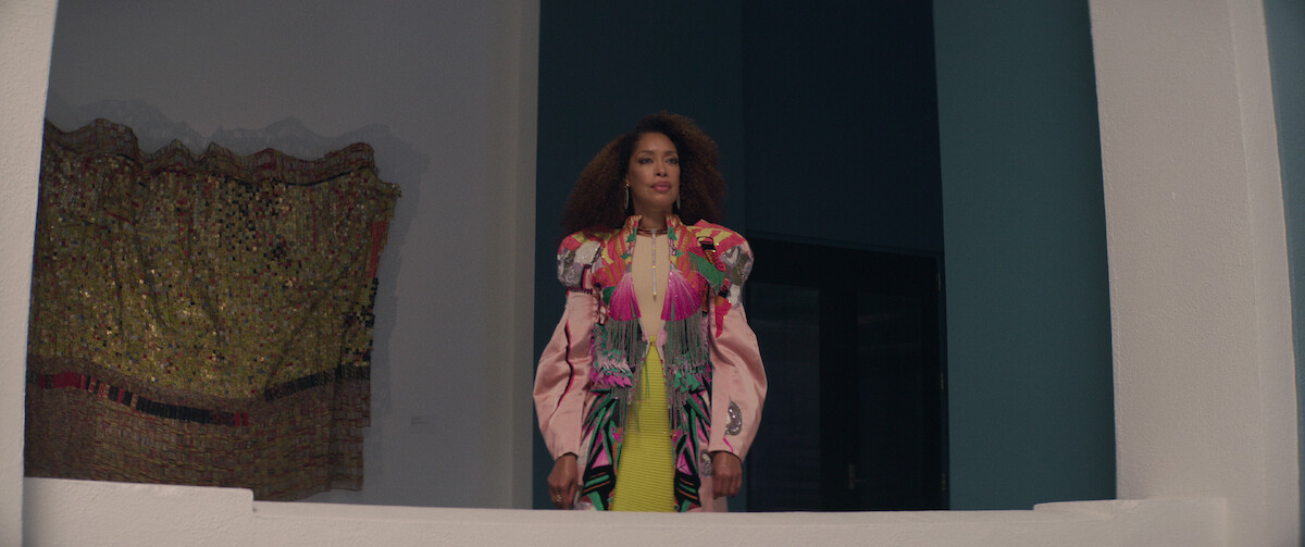 Gina Torres commands attention from a balcony in a colorful coat as Darcy in a still from ‘The Perfect Find.’