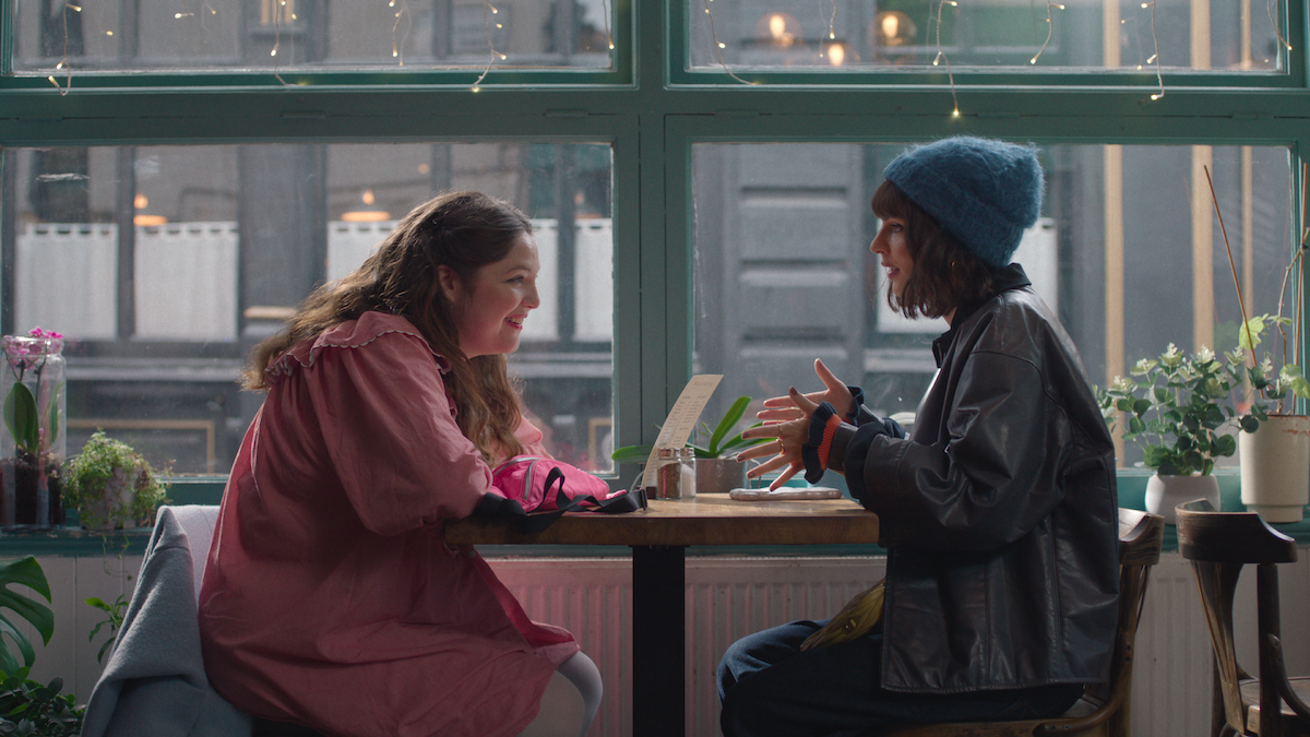 Megan Stalter as Jessica and Emily Ratajkowski as Wendy Jones sitting at a café in ‘Too Much’