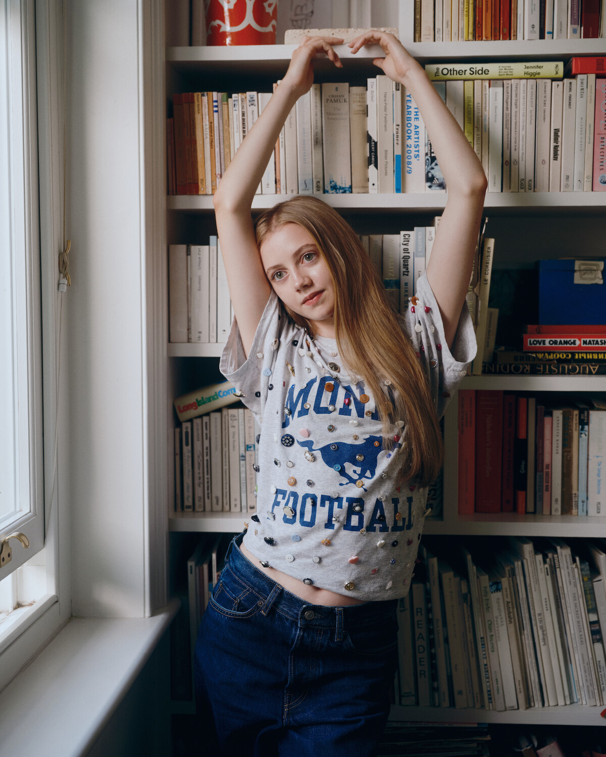 Evie Templeton poses in front of a bookshelf.