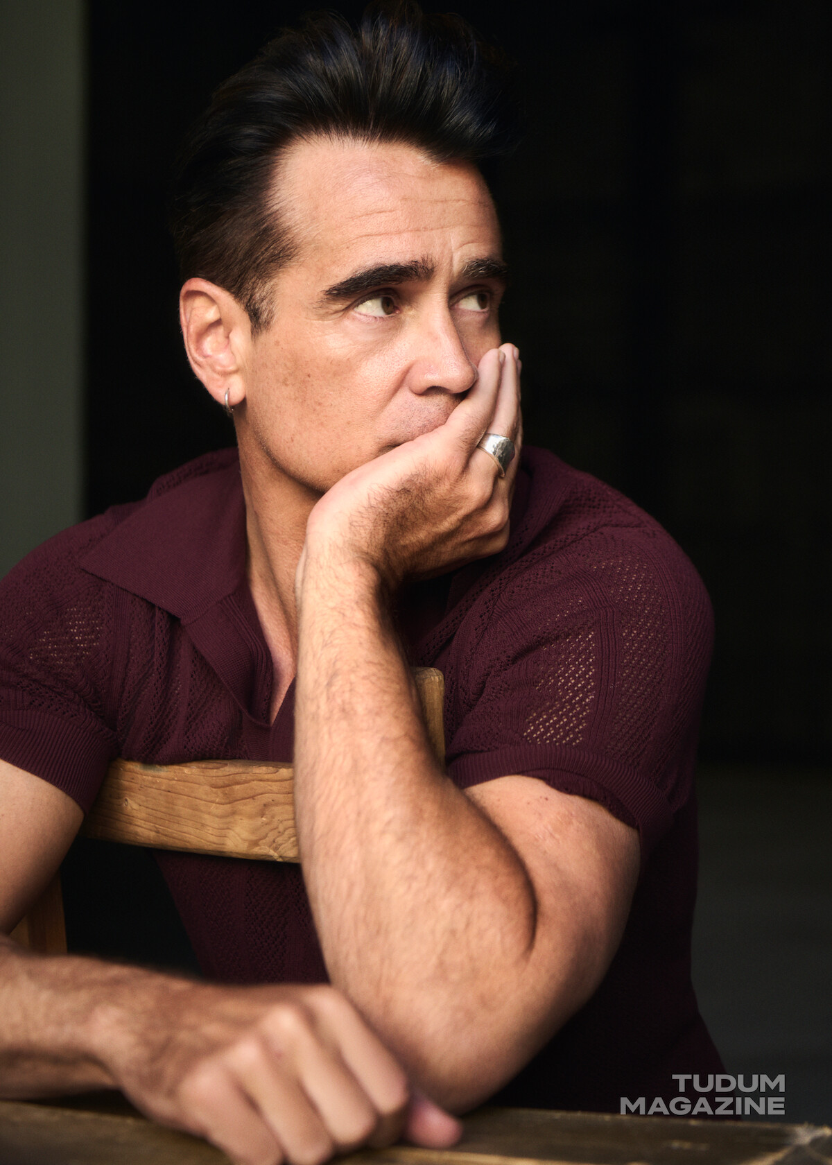 Colin Farrell looks away from the camera while wearing a maroon polo.