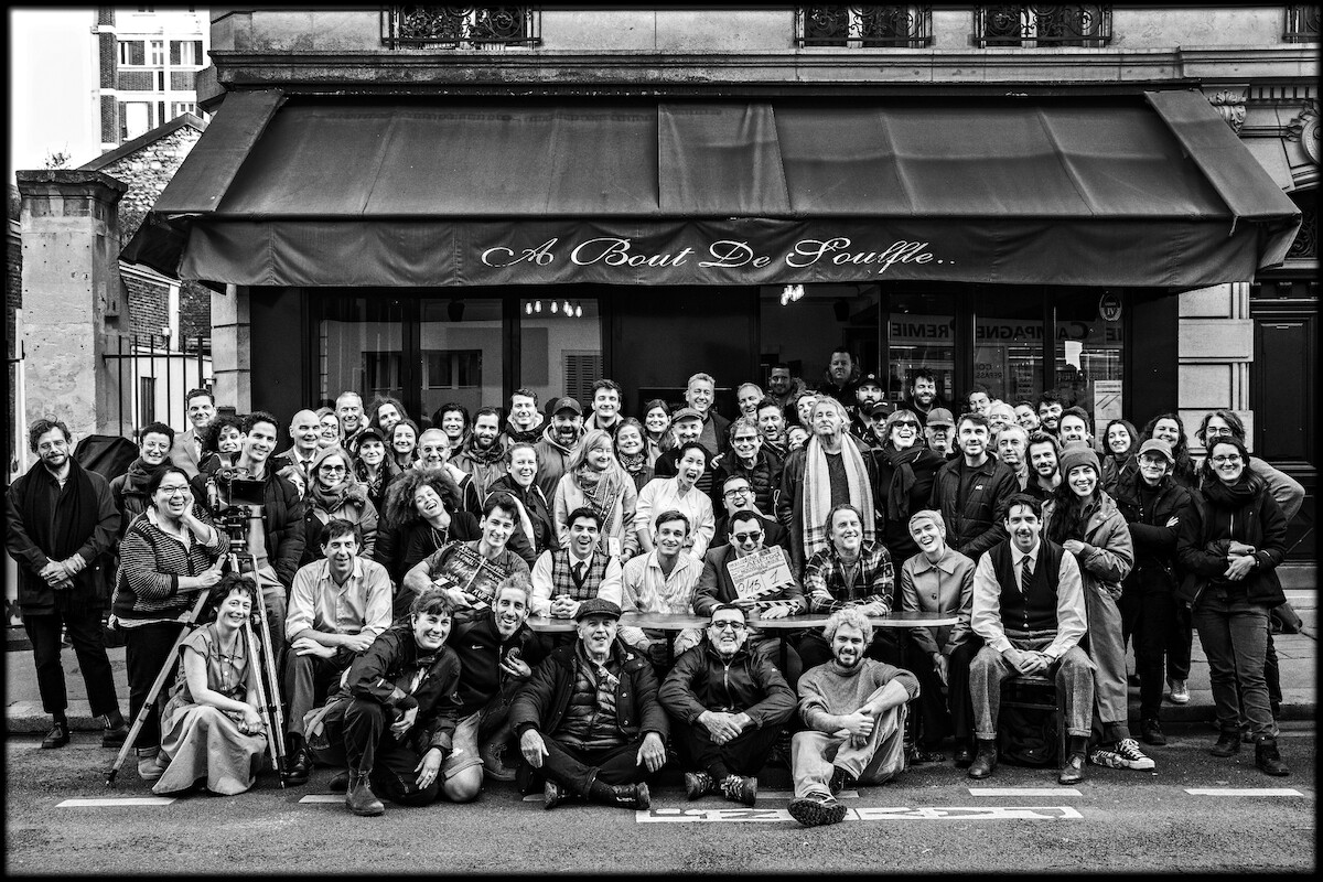 The crew of Nouvelle Vague sit in front of a cafe