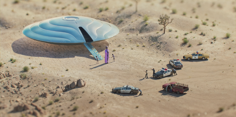 In a desert scene, a flying saucer has landed as aliens greet humans, while police cars, a taxi, and a pickup truck form a line nearby. The scene has a playful, miniature diorama look.