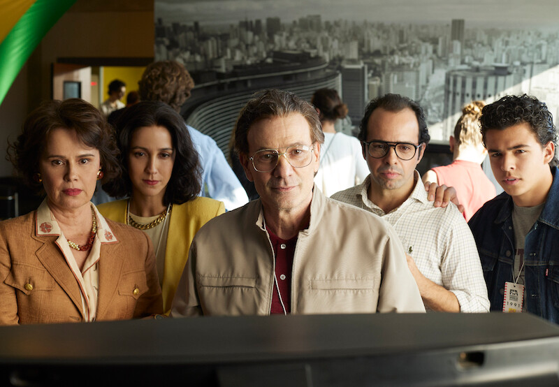  Susana Ribeiro as Zaza, Camila Mardila as Viviane Senna, and Marco Ricca as Miltão stand together watching a monitor in 'Senna'