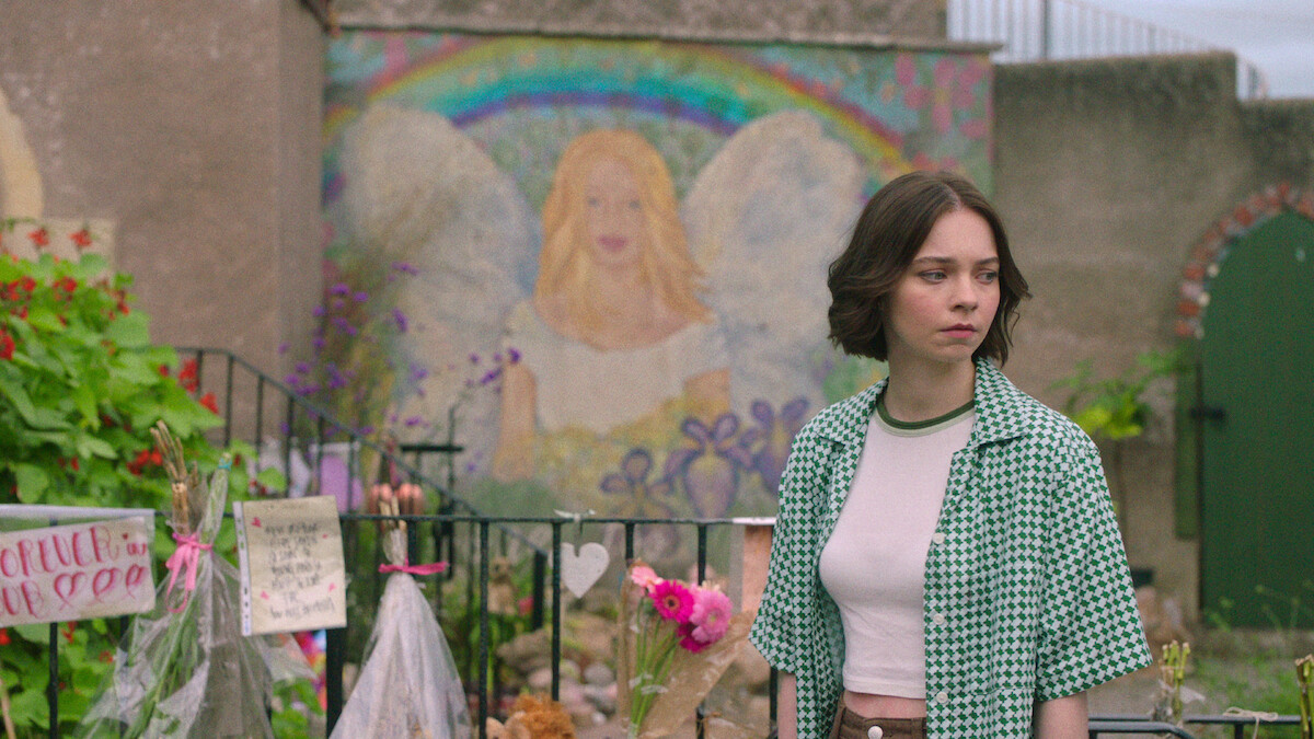 Emma Myers as Pip stands in front of a memorial mural in ‘A Good Girl’s Guide to Murder’
