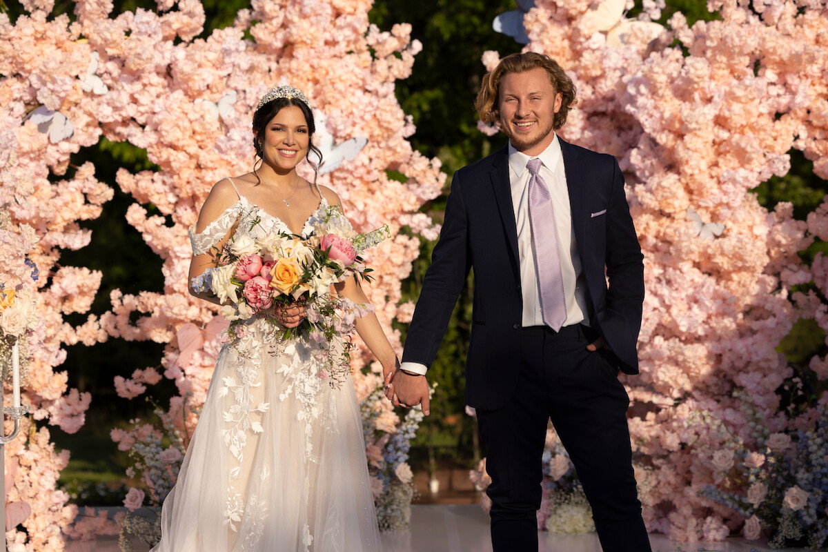 Amy and Johnny stand at an altar shrouded in pink flowers in season 6 of ‘Love Is Blind’