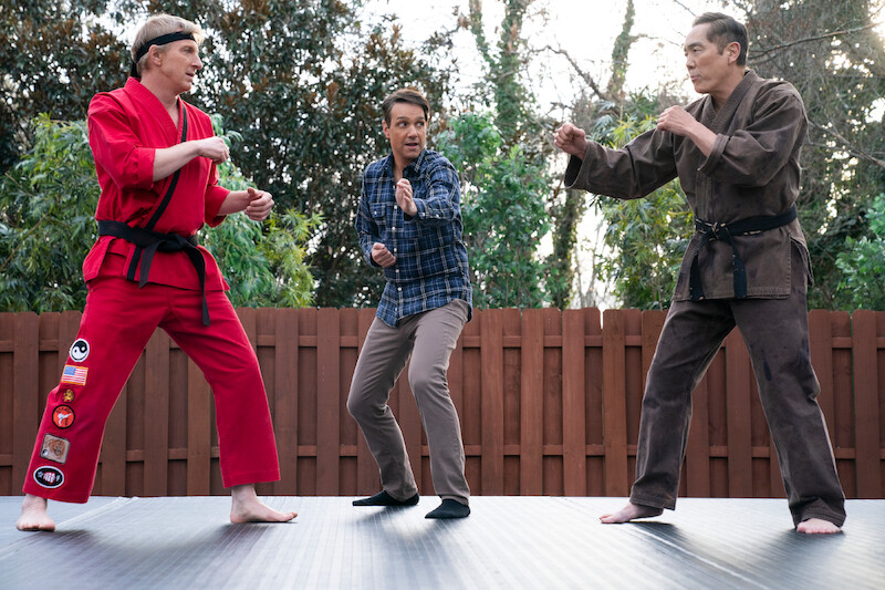 William Zabka as Johnny Lawrence, Ralph Macchio as Daniel LaRusso, and Yuji Okumoto as Chozen in stand in fighting positions in Season 6 of 'Cobra Kai.'