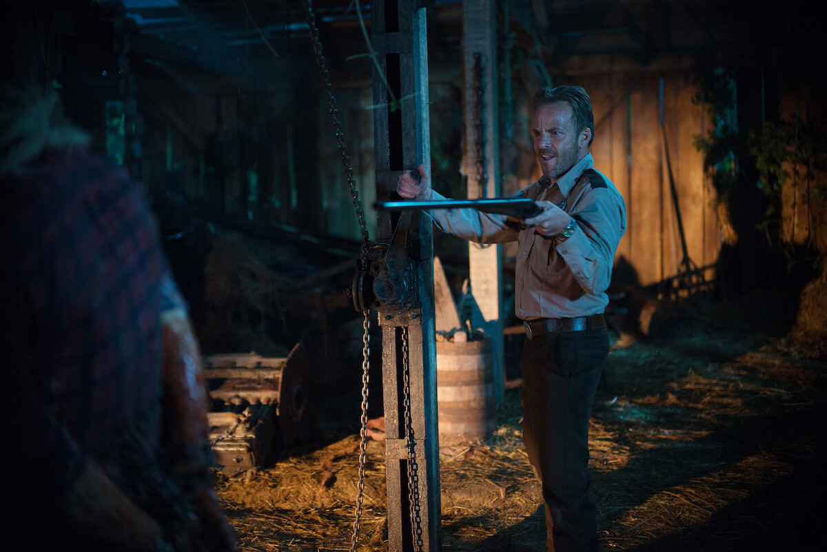Close up of a sheriff aiming a gun at Leatherface
