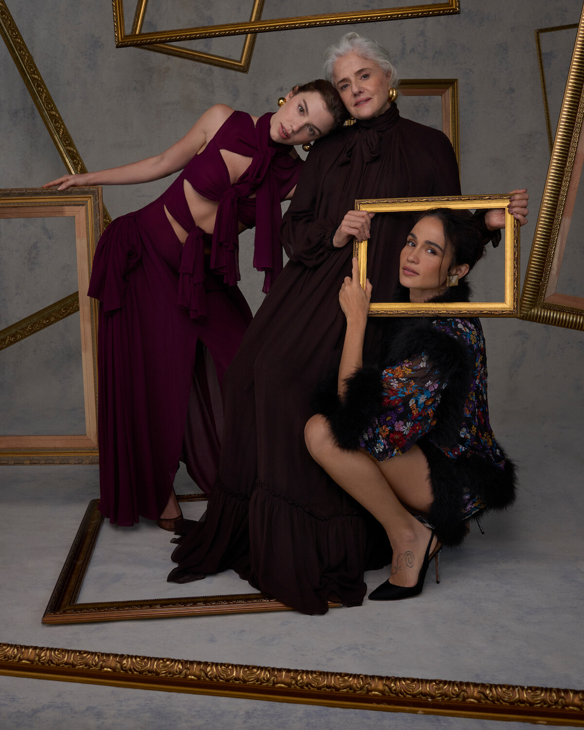 As atrizes Alice Wegmann, Marieta Severo e Nanda Costta posam para fotos em um ambiente repleto de molduras de quadro douradas