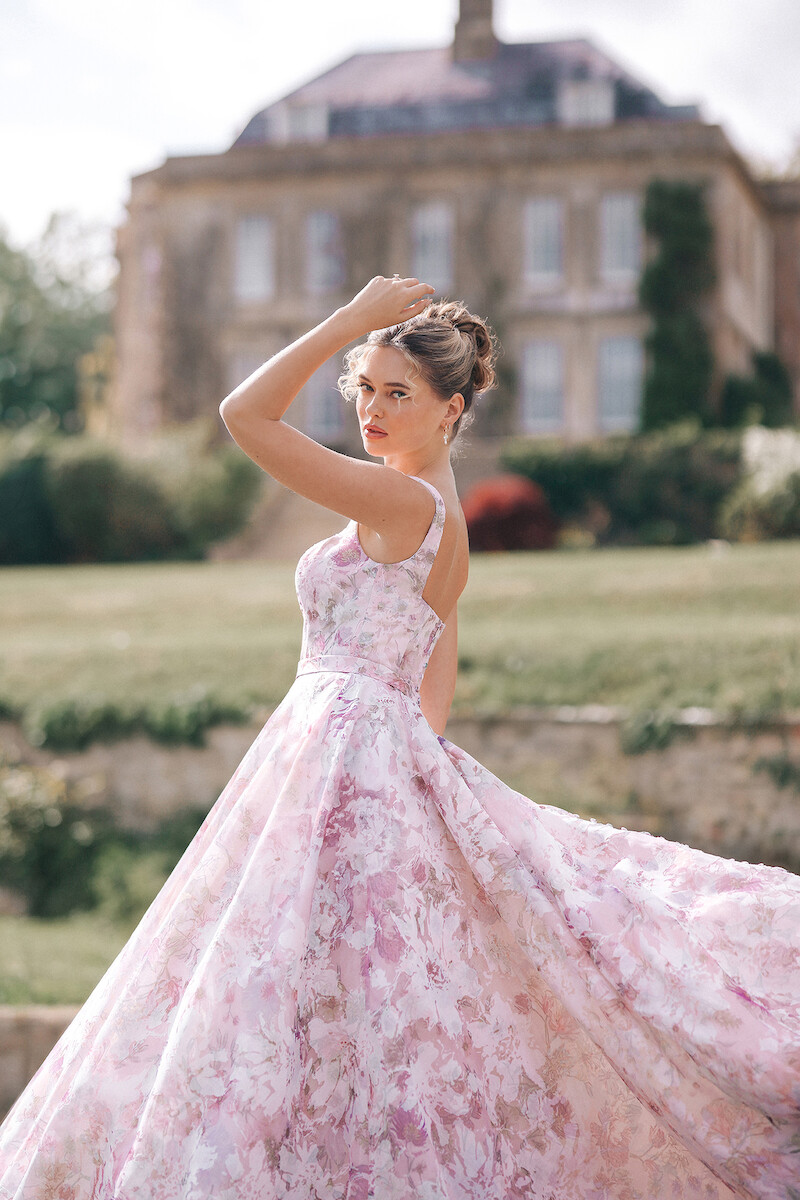 Woman in bridal dresses poses and looks off into the distance.