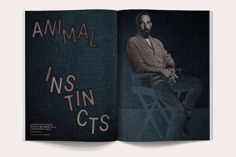 Magazine spread featuring a bearded man in a sweater and pants seated on a director’s chair on the right, with the headline "Animal Instincts" in large text on the dark background to the left.