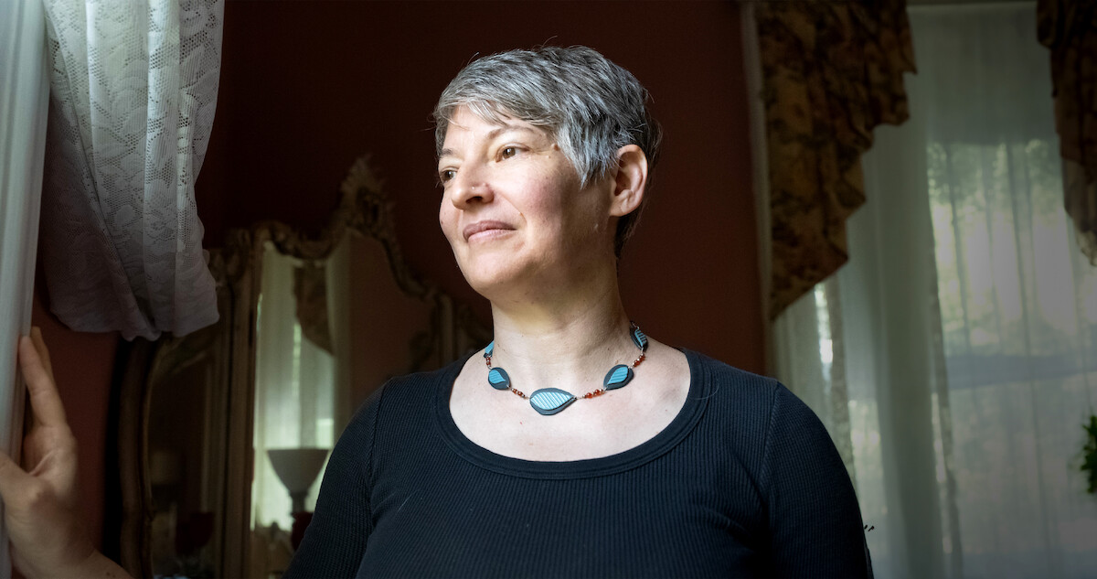 Anna Stubblefield sits in front of a curtained window wearing a black shirt in an image from the documentary film ‘Tell Them You Love Me’