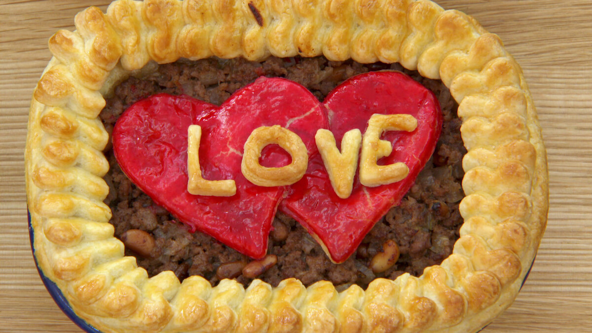 A pie featuring a crust made out of pastry-shaped hearts with a big heart in the middle of the pie that says