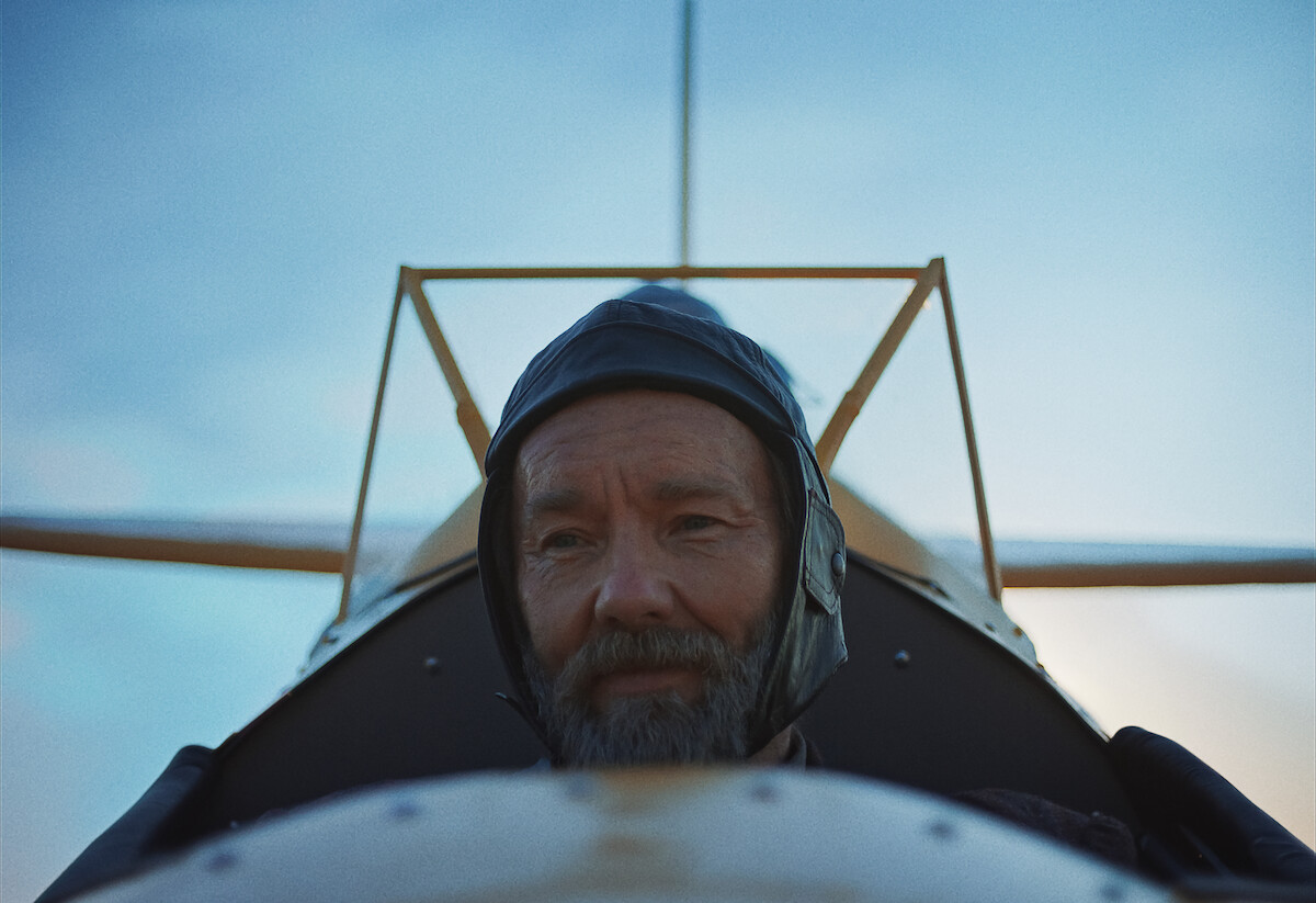Joel Edgerton wearing a helmet in an airplane.