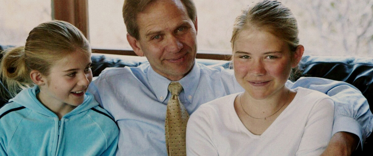 Young Elizabeth and her sister and father sit on the couch.