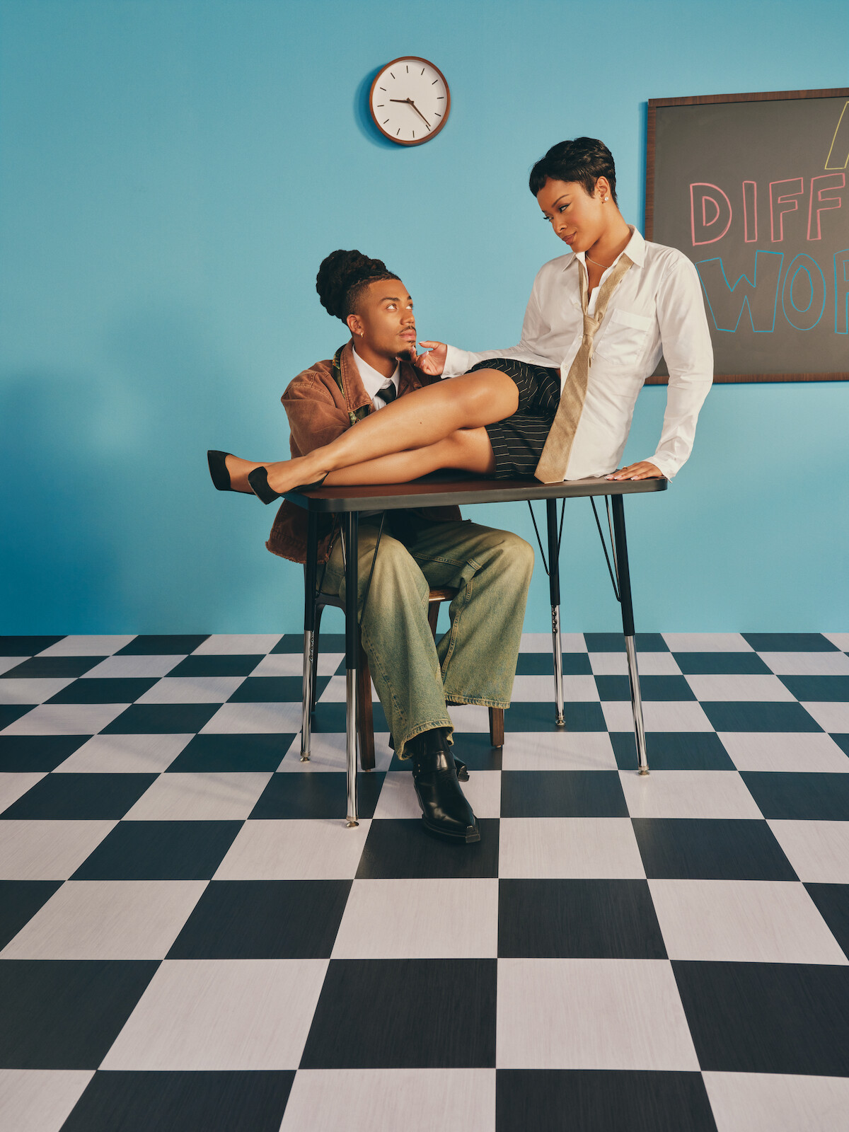 Two people in a classroom with a blackboard and clock, one sitting on a desk with legs across the other's lap, both dressed in semi-formal attire, on a black-and-white checkered floor and blue wall background.