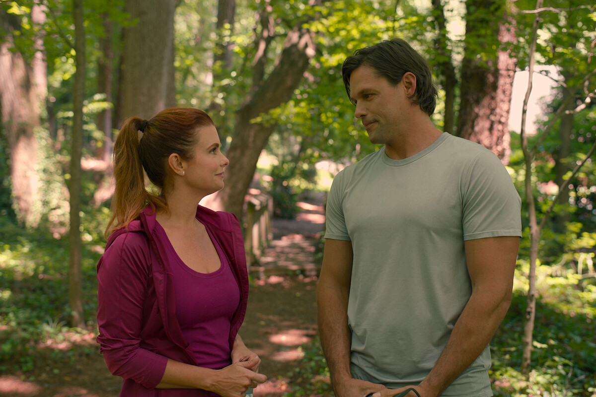 JoAnna Garcia Swisher as Maddie and Justin Bruening as Cal, wearing athletic clothes and looking into each other’s eyes in Season 3 of ‘Sweet Magnolias.’