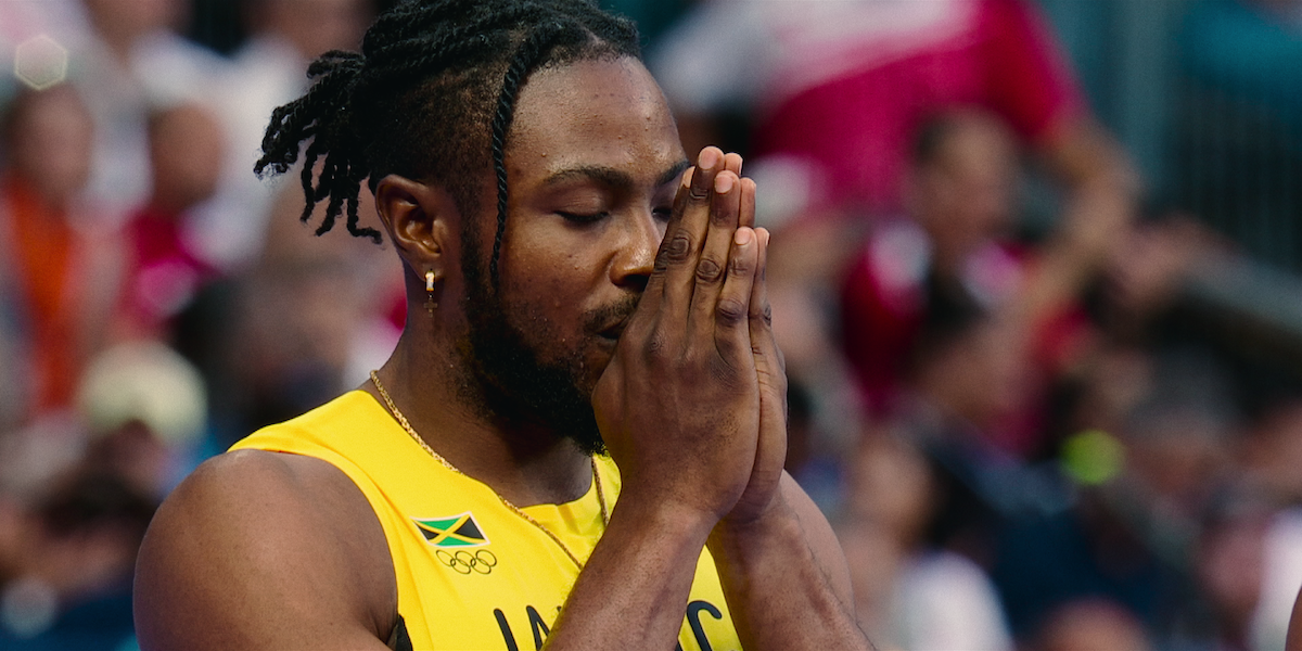 Kishane Thompson with his hands clasped together in prayer before a race.
