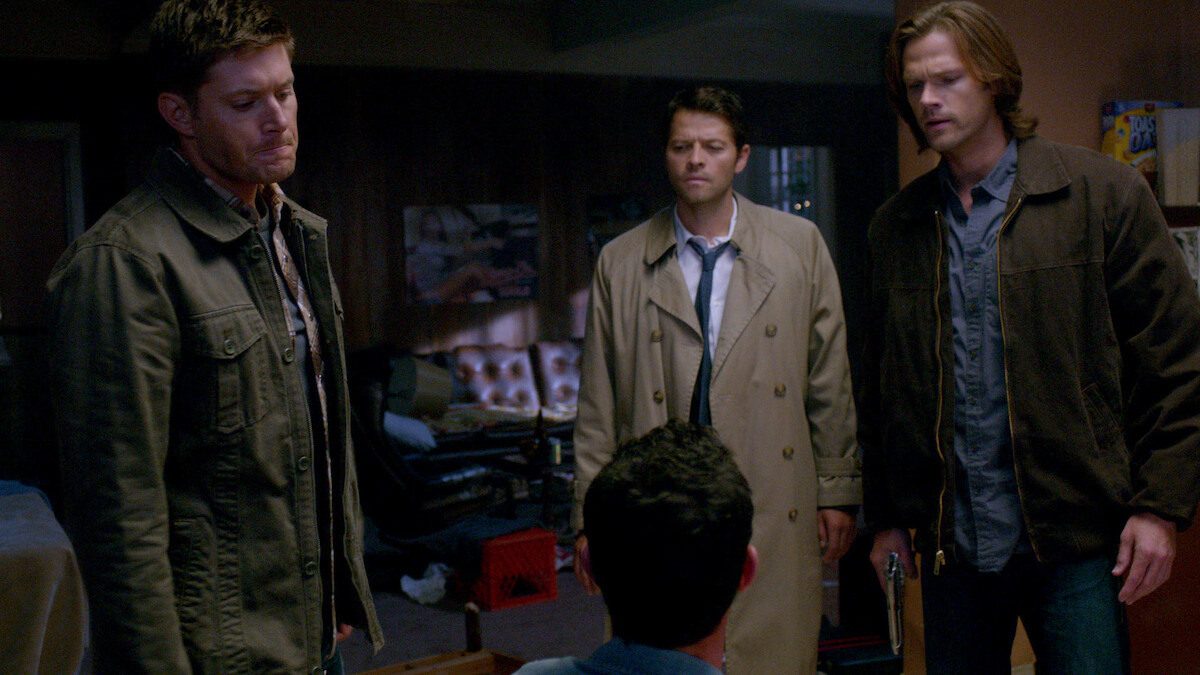 3 Men staring down at someone who is sitting down