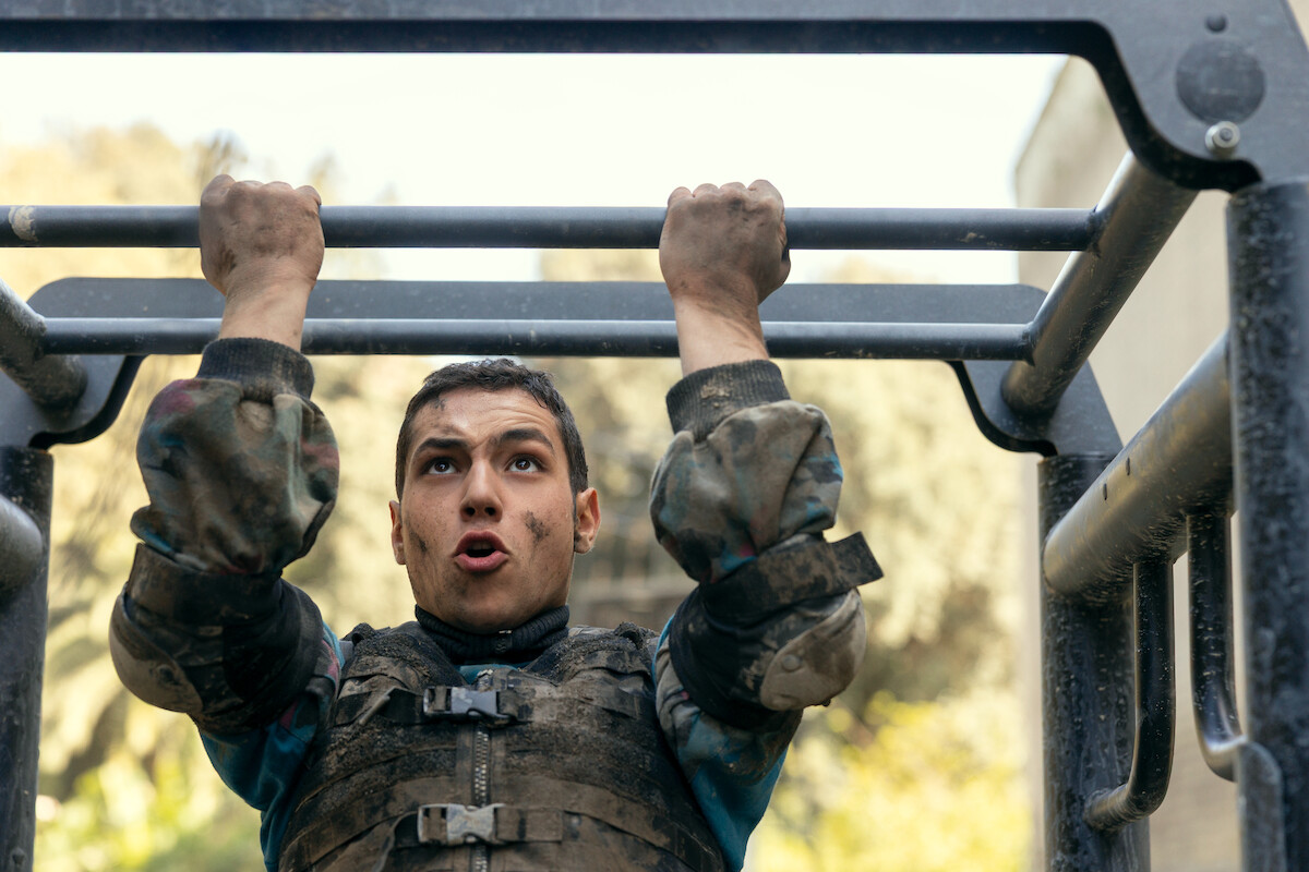 Um homem de cabelos curtos faz exercícios em trajes militares durante uma prova