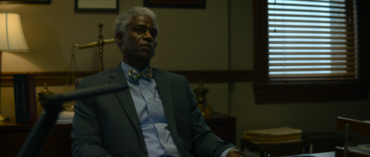 Charles Parnell as The Lawyer sits at a deck in ‘The Killer’
