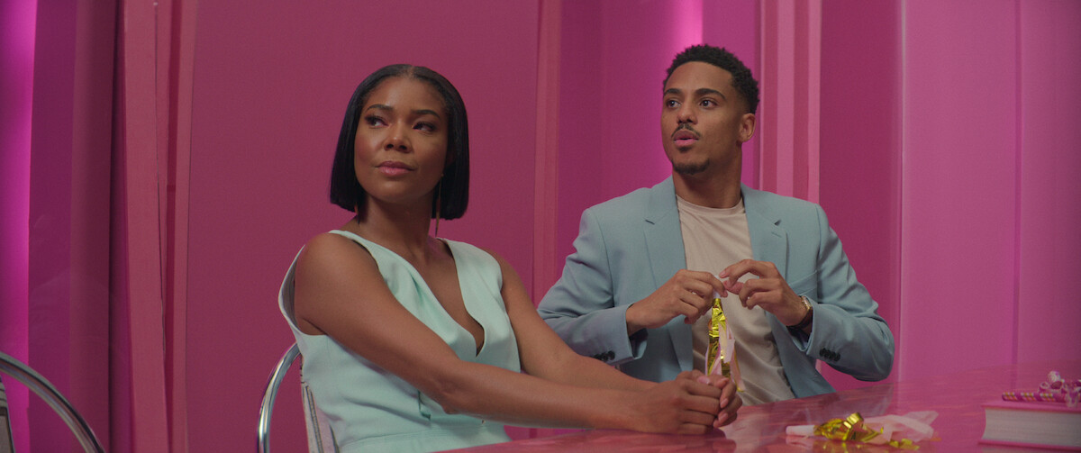 Gabrielle Union and Keith Powers sit side-by-side in a hot pink conference room in a still from ‘The Perfect Find.’