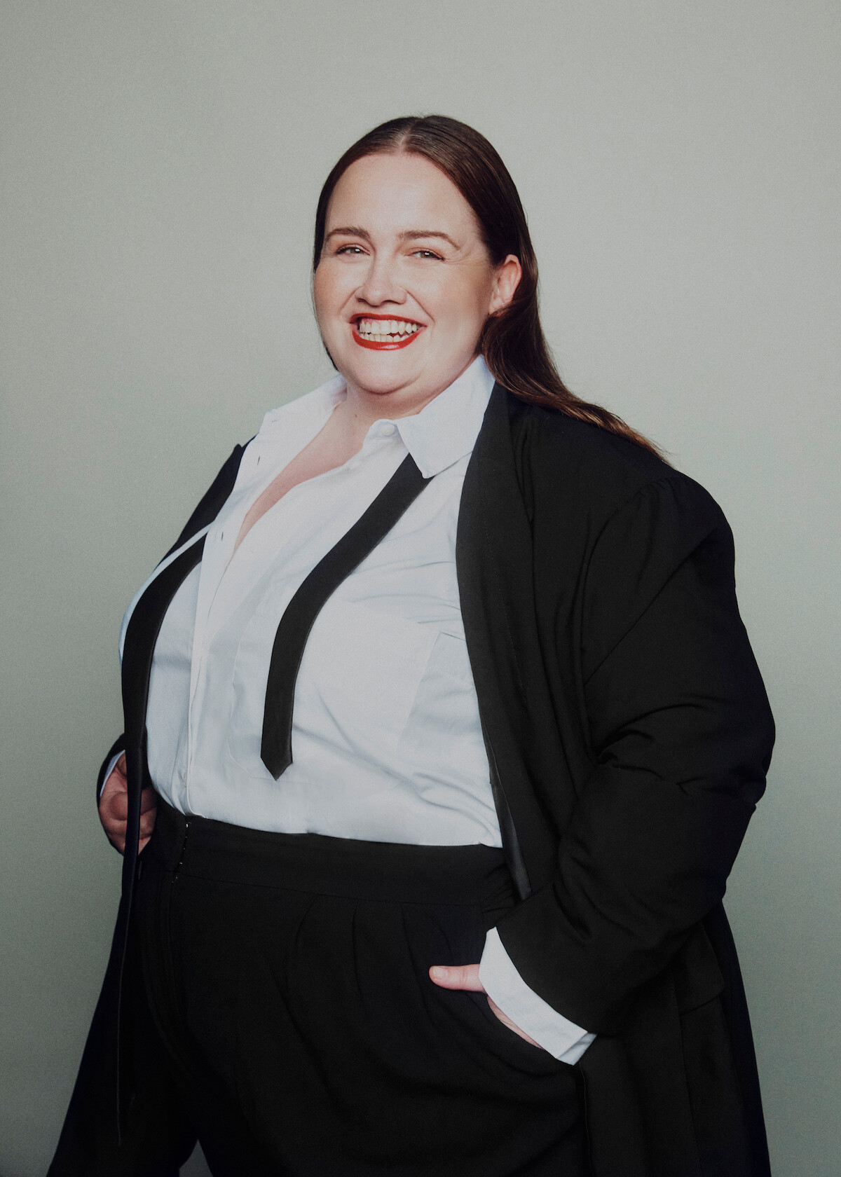 Jessica Gunning wears a suit and smiles with her hands in her pockets.